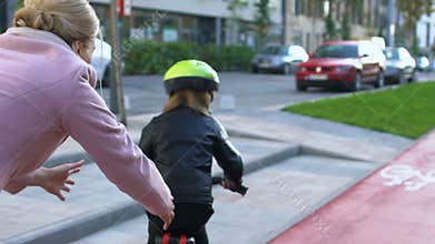 Loving mother helping daughter learning to ride bicycle outdoors, connection