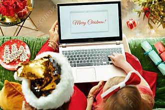 Modern mother and child writing Merry Christmas email