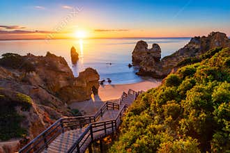 Sunrise at Camilo beach in Lagos, Algarve, Portugal. Wooden footbridge to the beach Praia do Camilo, Portugal. Picturesque view of