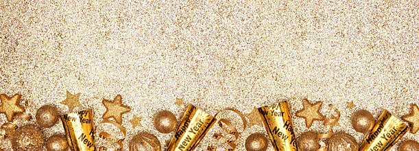 New Years Eve border banner of gold decorations, steamers and noisemakers, above view over a glittery gold background