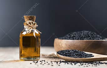 Black cumin seeds essential oil , Nigella Sativa in spoon on wooden background