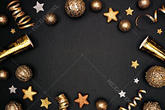 New Years Eve frame of glittery gold stars, streamers, decorations and noisemakers, above view on a black background