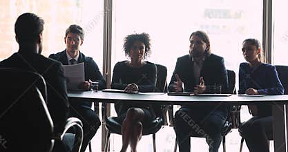 Interviewers group representative speaking to male applicant during job interview