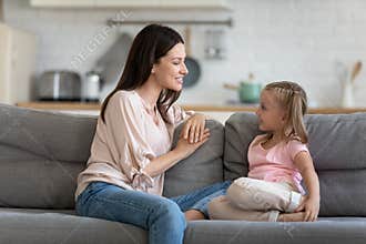 Happy mother and cute child enjoy talking relaxing on sofa