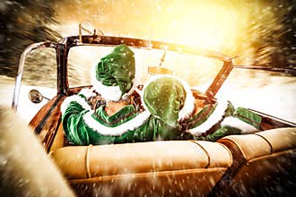 Two Elves in a car driving to deliver some christmas presents on a sunny winter day. Christmas decor on gold red background.