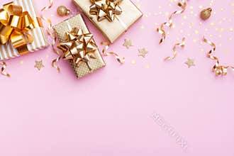 Christmas banner. Golden gift or present boxes and star confetti on pink background top view. Flat lay