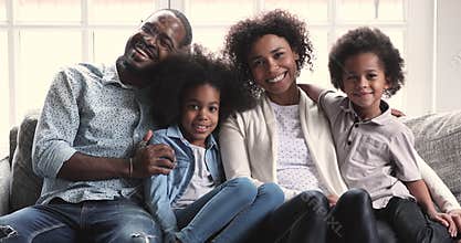 African parents posing for portrait sit with children on sofa