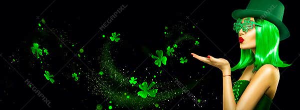 St. Patrick`s Day leprechaun model girl pointing hand, holding product, isolated on black magic background, blowing shamrock leave