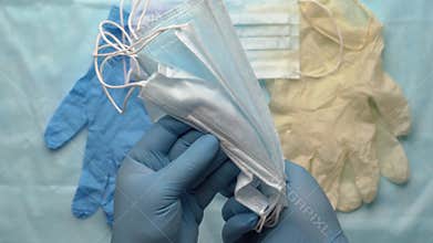 Doctor showing surgical face mask holding equipment in his hands protected by blue medical gloves. Pandemic insurance coronavirus
