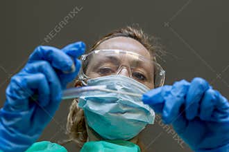 A blonde white woman working as a lab technician performs a swab to check for a possible Coronavirus Covid-19 infection