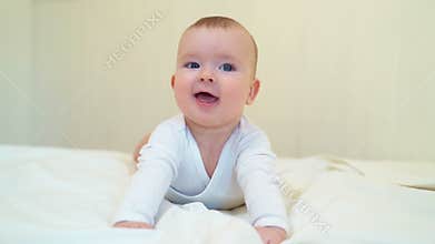 Baby in white clothes lying on paunch on white bed