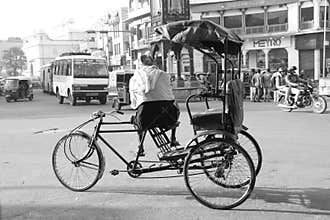 Tricycle man sits waiting for passengers on a cross road