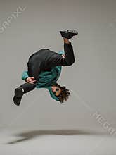 Boy dancing breakdance mid-air in studio. Acrobatic dancer.