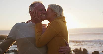 Senior couple embracing each other alongside beach