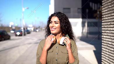 Young arab woman walking in the street with headphones