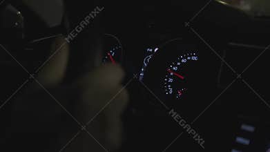 A close-up of car dashboard while man drive for city streets at night.