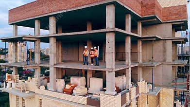 Three construction workers talk while standing on a site. Multiethnic engineers, architects discussing construction plan
