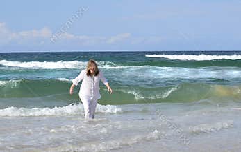 Senior woman playing sea gets surprised by cold surf wave