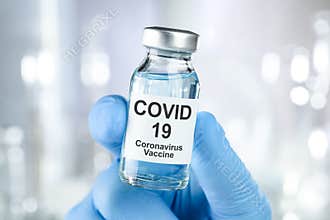 Healthcare cure with a hand in blue medical gloves holding Coronavirus, Covid 19 virus, vaccine vial