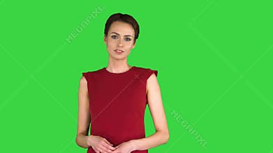 Excited beautiful young woman in red dress talking to camera on a Green Screen, Chroma Key.