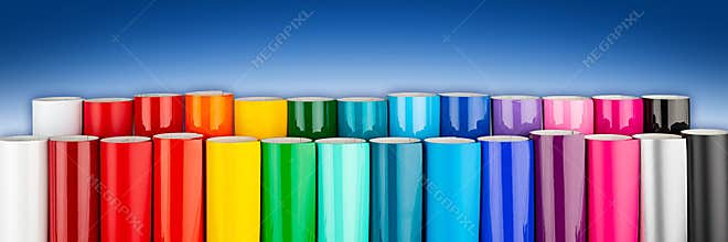 Row of various rainbow colored vinyl car wrapping or plotter cutting sticker foil film rolls  blue white wide panorama banner