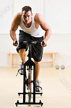 Man riding stationary bicycle in health club