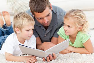 Father and children reading a book on the floor