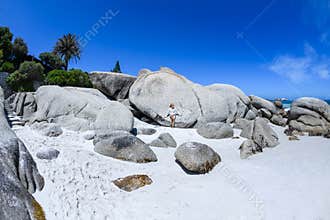 A young woman sittingon the boulders of clifton beach in the capetown area of south africa.5