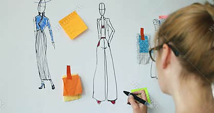 Fashion designer sketching her new clothing collection on whiteboard