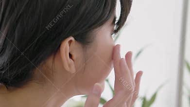 Beautiful young asian woman smiling look at mirror of checking face and skin care cream and cosmetic