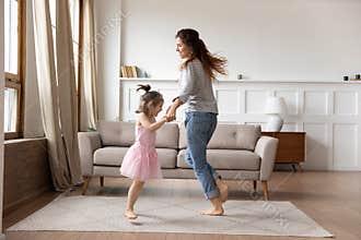 Happy mother and little daughter wearing princess dress dancing