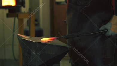 Blacksmith hammering hot iron in the smithy