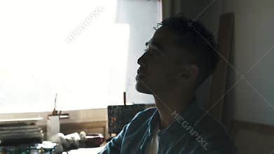 Young attractive painter contemplating his artwork