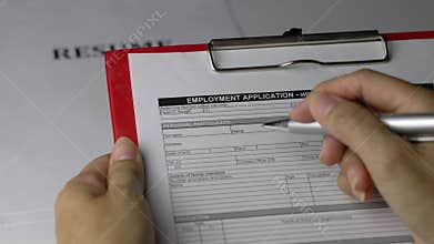 Woman holding an employment application form on top of resume on office table.