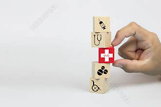Close-up hand choose a cube wooden toy blocks with a red cross heart rhythm icon stacked.