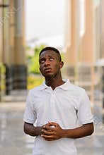 Portrait of stressed young African man praying and looking up outdoors