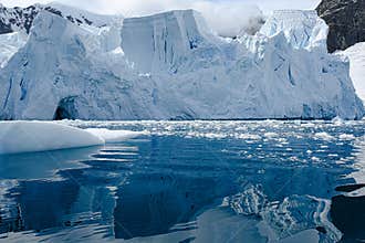Glacier ice shelf in Antarctica, majestic blue and white glacier edge reflecting in blue sea water, Paradise Bay, Antarctica