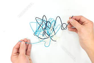Hand fixing tangled yarn. Critical thinking, problem solving and psychotherapy concept