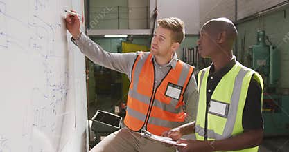 A Caucasian and an African American male factory worker holding a clipboards