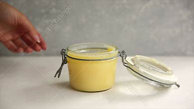 Ghee or melted butter in a jar on wooden table. get a silver spoon from a can.