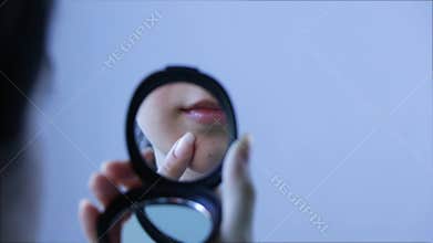 A woman looks at a pimple on her face in the mirror. Close up. Acne, redness, blemishes, blackheads. Skin care, cosmetology. Teen,