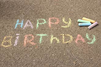 Happy birthday written in colored crayons on the sidewalk