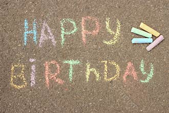 Happy birthday written in colored crayons on the sidewalk