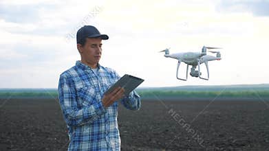 Smart farming tech agriculture farming. man farmer engineer studies a farmland in black mud dirt field using a