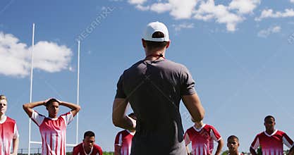 Coach talking to rugby players on the field