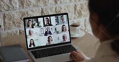 Over shoulder view of employee communicating with team by webcam