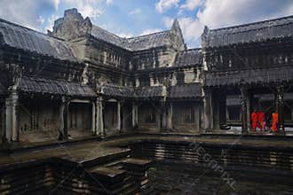 Overcast cloud rain & a group of monks in bright orange robes standing with umbrellas at Angkor Wat temple, Siem Reap, Cambodia
