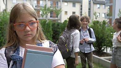 Portrait of a sad schoolgirl. Group of schoolchildren mock the girl. Child cruelty. School bullying.