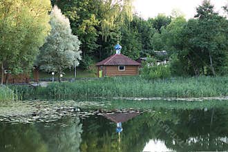The bathhouse of the Orthodox Church is reflected in the river. Summer, Park, reeds. Symbols of faith in God. Religion. The