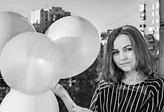 Young girl with balloons on the balcony of the apartment. Birthday. Black and white